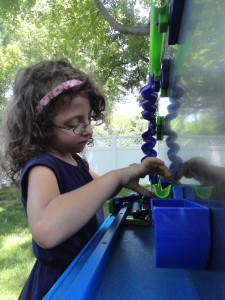 Lucy learns about friction and kinetic energy by playing with the magnetized marble slides at our summer reading kickoff party.