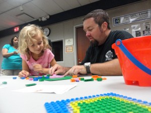 Ellie and Jason answer a math problem using Lego during the Family Lego Challenge.
