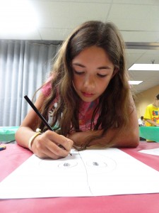 Abby draws Hula, a superhero she created.