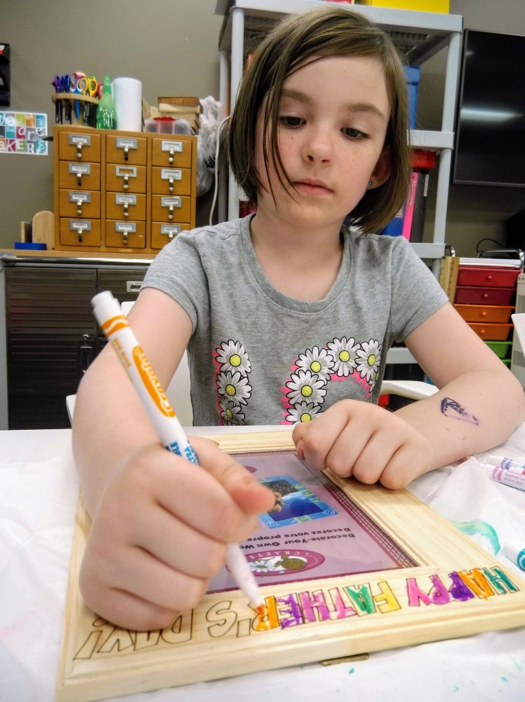 Estella decorates the picture frame she had engraved for Father's Day at the makerspace in The HUB.