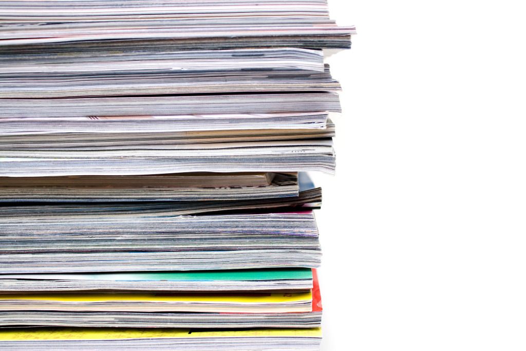 A large stack of magazines piled high.  Isolated over white with copyspace.